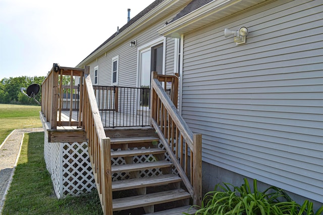 entrance to property with a deck and a lawn