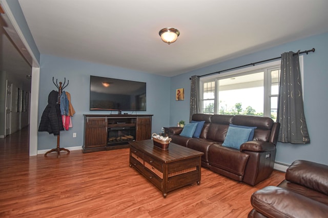 living room with a baseboard heating unit and light wood-type flooring