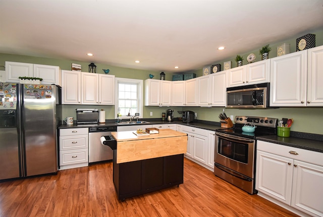 kitchen with appliances with stainless steel finishes, wood-type flooring, and white cabinetry