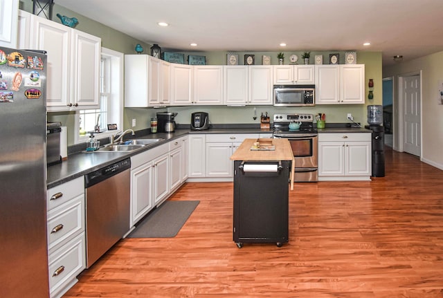 kitchen with a kitchen island, wood counters, white cabinets, light wood-type flooring, and appliances with stainless steel finishes