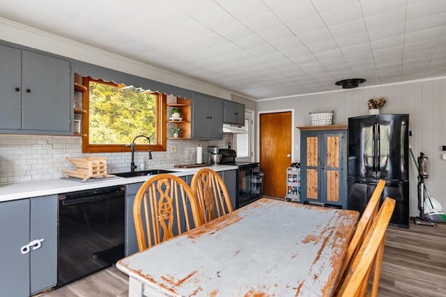 kitchen featuring light hardwood / wood-style floors, decorative backsplash, black appliances, and wooden walls