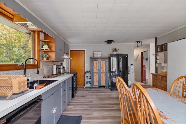 kitchen with gray cabinetry, tasteful backsplash, black appliances, sink, and light hardwood / wood-style floors