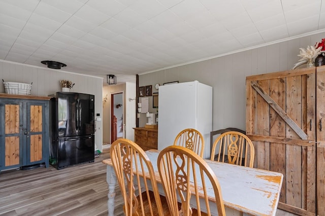 dining room featuring crown molding, light hardwood / wood-style floors, and wood walls