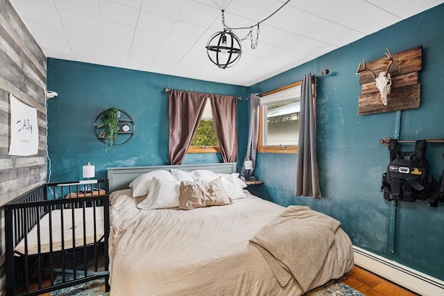 bedroom with hardwood / wood-style flooring, a baseboard radiator, and a chandelier