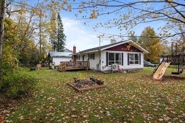 rear view of house featuring a yard, a deck, and a playground