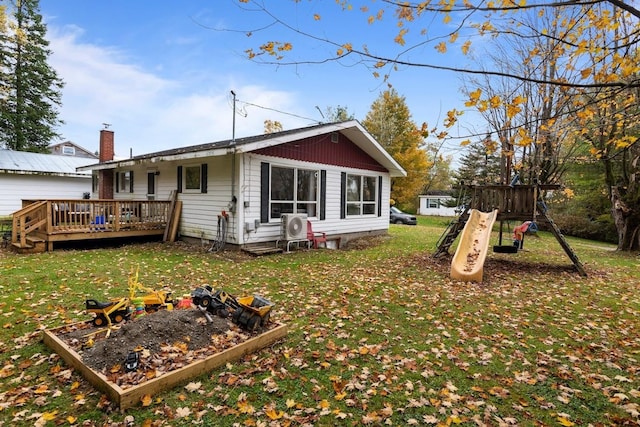 rear view of property featuring a yard, a playground, and a wooden deck