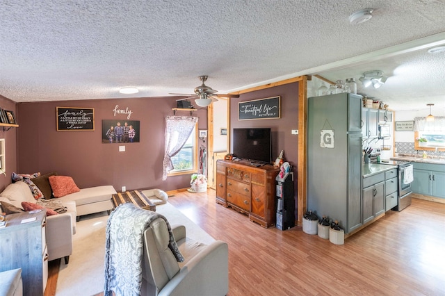 living room with ceiling fan, a textured ceiling, and light hardwood / wood-style flooring