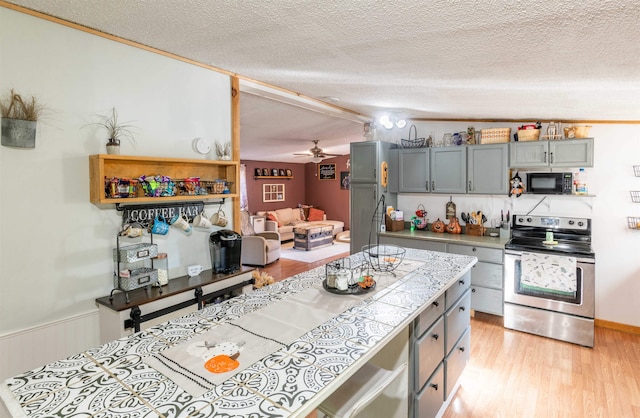 kitchen featuring lofted ceiling, ceiling fan, a textured ceiling, stainless steel electric range oven, and light hardwood / wood-style flooring