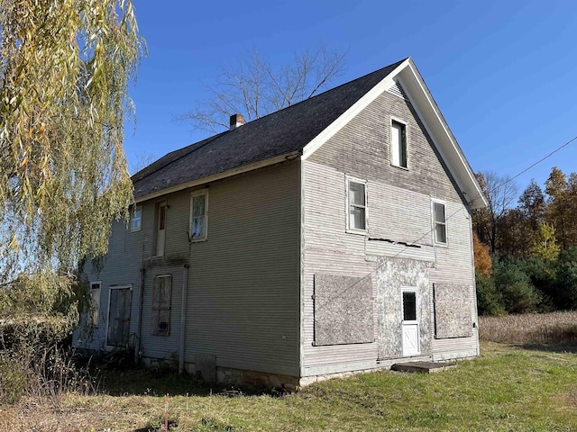 view of side of property with a chimney and a lawn