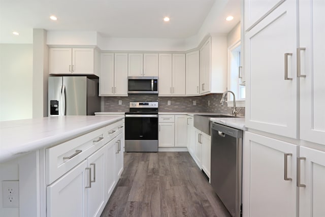 kitchen with appliances with stainless steel finishes, white cabinetry, sink, and hardwood / wood-style floors