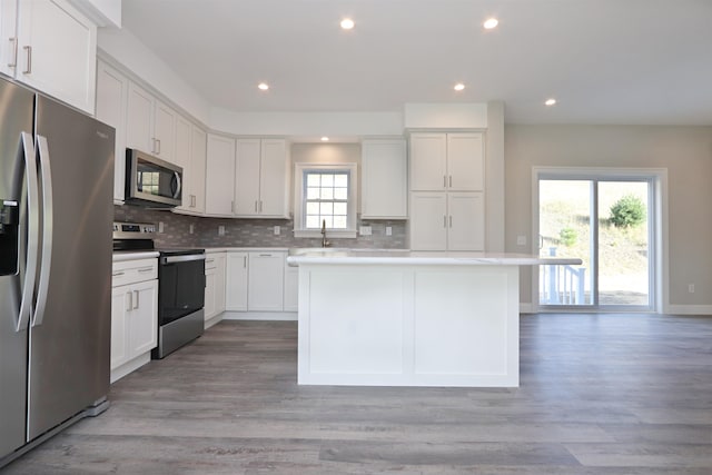 kitchen with a kitchen island, white cabinets, stainless steel appliances, and light wood-type flooring