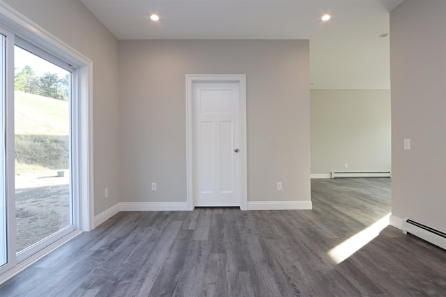 spare room with a baseboard radiator and dark hardwood / wood-style floors