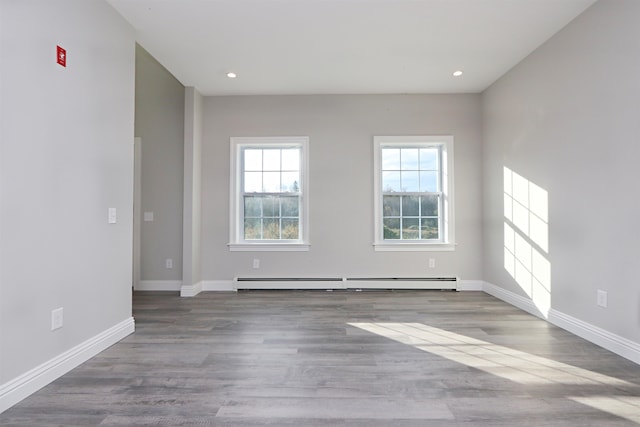 unfurnished room with a baseboard heating unit and light wood-type flooring