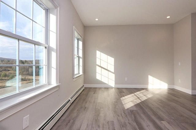 unfurnished room featuring hardwood / wood-style floors and baseboard heating