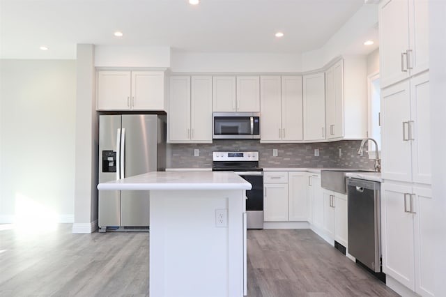 kitchen with white cabinetry, stainless steel appliances, light hardwood / wood-style flooring, and a kitchen island