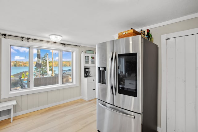 kitchen featuring a water view, wooden walls, light wood-type flooring, and stainless steel fridge