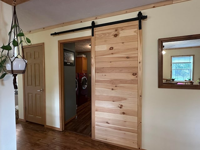 hallway with a barn door, dark hardwood / wood-style floors, and separate washer and dryer