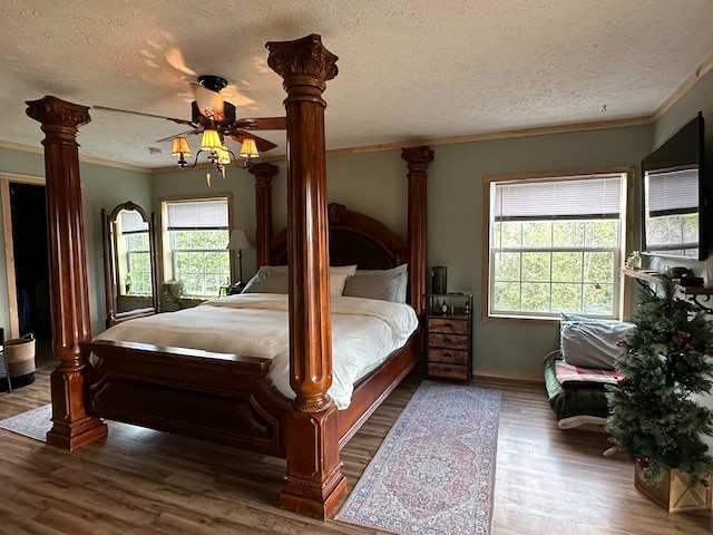 bedroom featuring ceiling fan, hardwood / wood-style flooring, a textured ceiling, and multiple windows