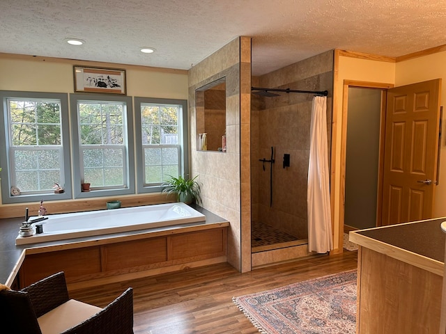 bathroom with ornamental molding, a textured ceiling, shower with separate bathtub, and hardwood / wood-style flooring