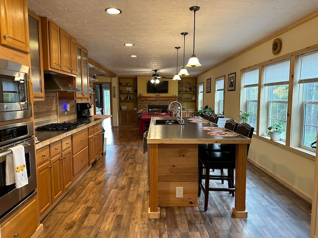 kitchen featuring a center island with sink, sink, a breakfast bar, appliances with stainless steel finishes, and ceiling fan