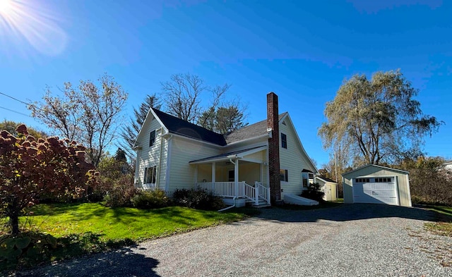 view of front of house with a front lawn, an outbuilding, a garage, and covered porch