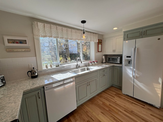 kitchen with decorative backsplash, white fridge with ice dispenser, sink, stainless steel dishwasher, and light hardwood / wood-style floors