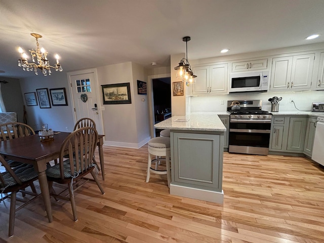 kitchen featuring light hardwood / wood-style floors, appliances with stainless steel finishes, decorative light fixtures, and kitchen peninsula