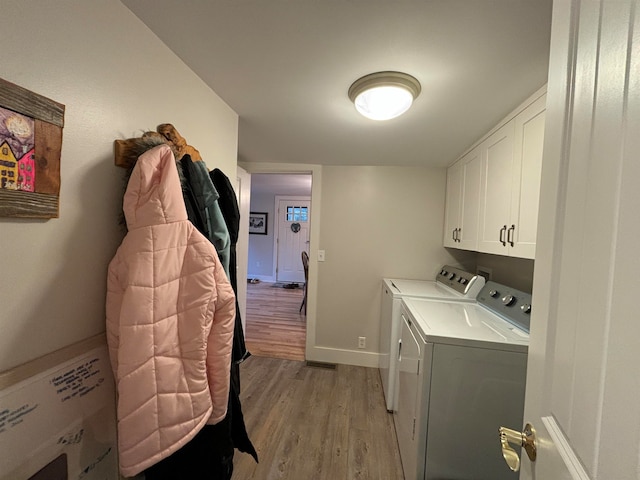 washroom featuring cabinets, light wood-type flooring, and washing machine and clothes dryer