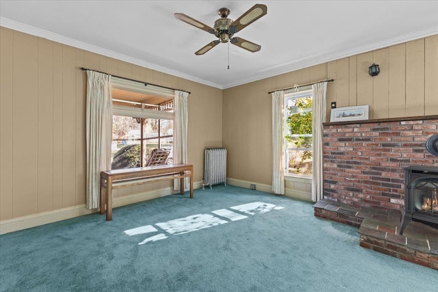 unfurnished living room featuring ornamental molding, a wood stove, radiator heating unit, and carpet