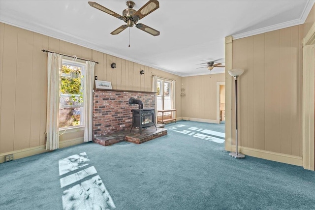 unfurnished living room featuring carpet flooring, a healthy amount of sunlight, a wood stove, and crown molding