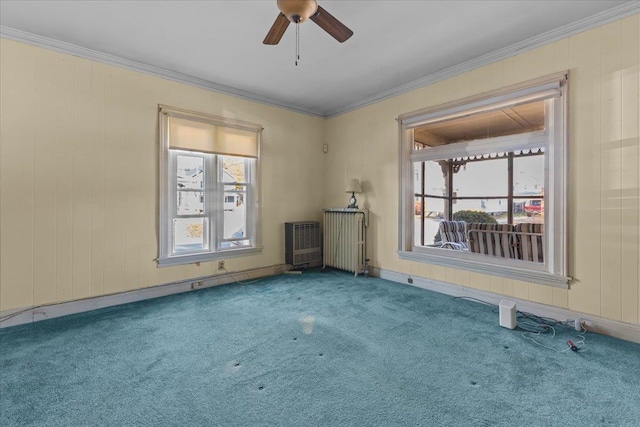 carpeted spare room featuring a wealth of natural light, ornamental molding, and radiator