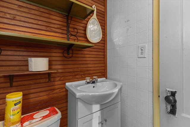 bathroom featuring vanity, toilet, and wooden walls