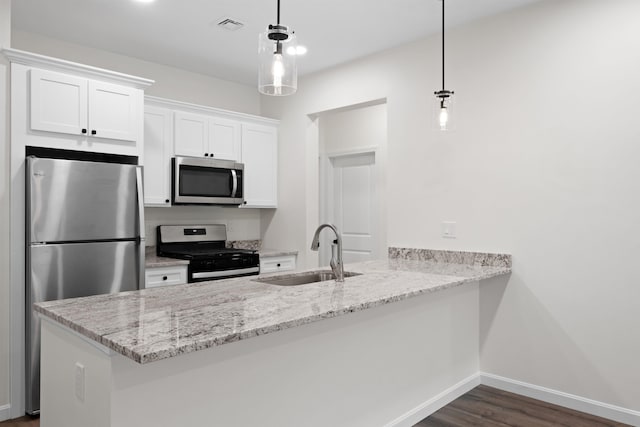 kitchen with appliances with stainless steel finishes, sink, kitchen peninsula, white cabinetry, and pendant lighting