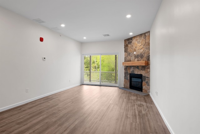 unfurnished living room with a stone fireplace and hardwood / wood-style floors