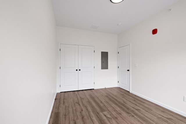 unfurnished bedroom featuring hardwood / wood-style floors, electric panel, and a closet