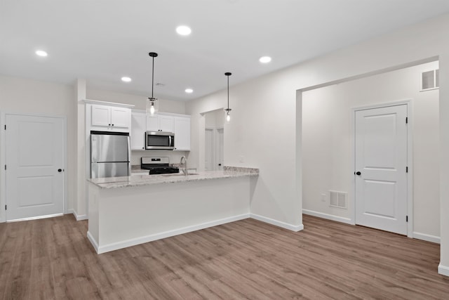 kitchen with white cabinetry, hanging light fixtures, stainless steel appliances, and light hardwood / wood-style floors