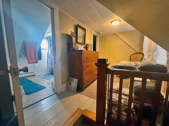 bedroom featuring hardwood / wood-style floors and a baseboard heating unit