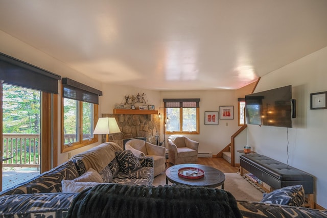 109 Upper Loop, Ludlow, VT 05149 - living area with wood finished floors, a baseboard radiator, stairs, and a stone fireplace