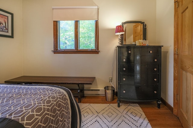 bedroom featuring wood-type flooring and a baseboard heating unit