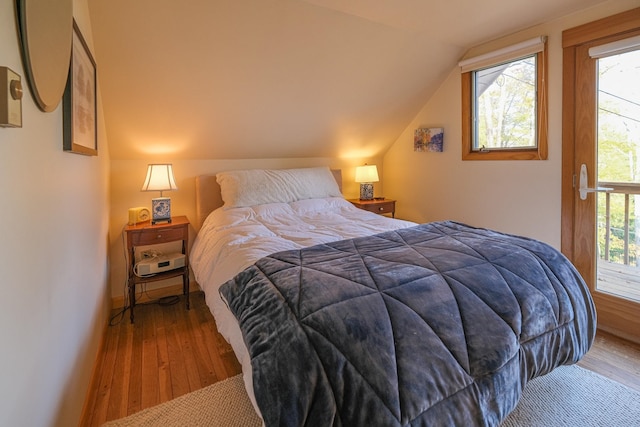 bedroom with hardwood / wood-style floors, multiple windows, and vaulted ceiling