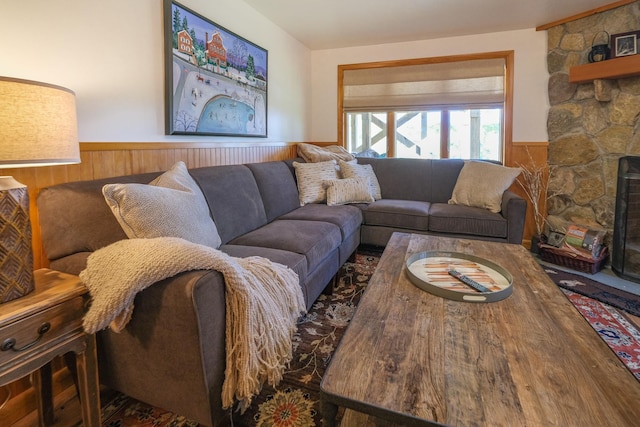 living room with a stone fireplace and wood walls