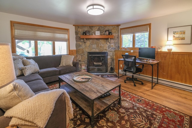 living room featuring a fireplace, hardwood / wood-style flooring, baseboard heating, and plenty of natural light