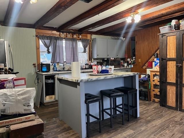 kitchen featuring beam ceiling, a center island, dishwashing machine, and dark hardwood / wood-style flooring