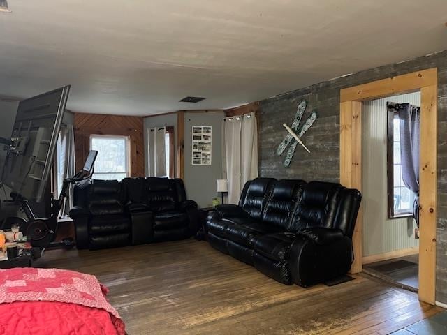 living room with wooden walls, dark hardwood / wood-style floors, and plenty of natural light