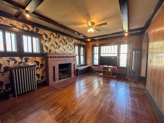 unfurnished living room with wooden walls, plenty of natural light, and dark hardwood / wood-style flooring