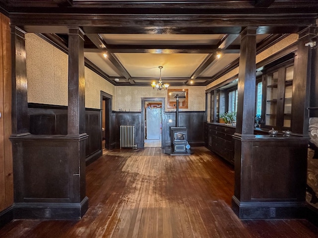 kitchen with a wood stove, radiator heating unit, coffered ceiling, beam ceiling, and dark hardwood / wood-style floors