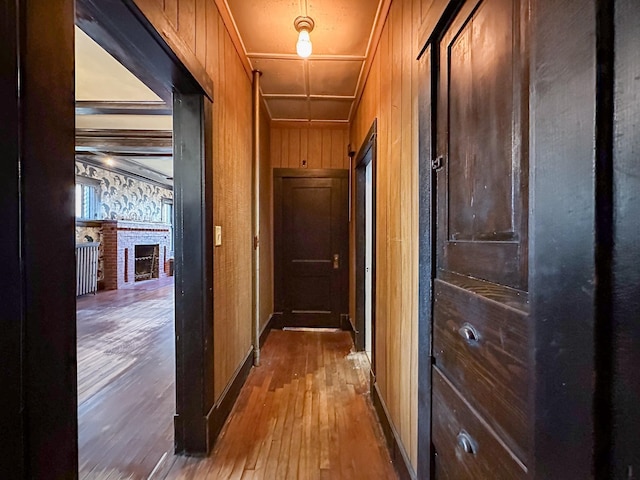 corridor with ornamental molding, wooden walls, and hardwood / wood-style flooring