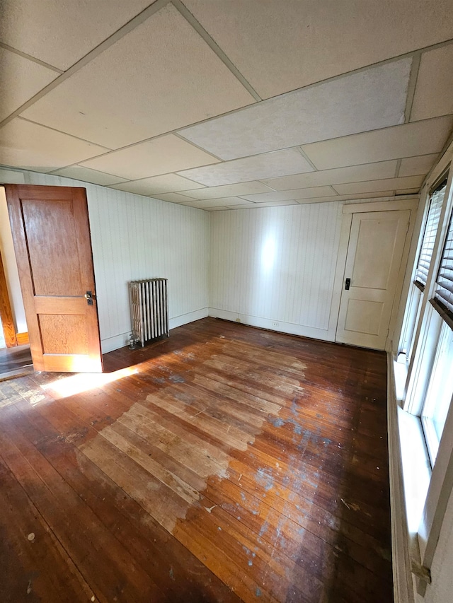 interior space featuring a healthy amount of sunlight, wood-type flooring, radiator heating unit, and wooden walls