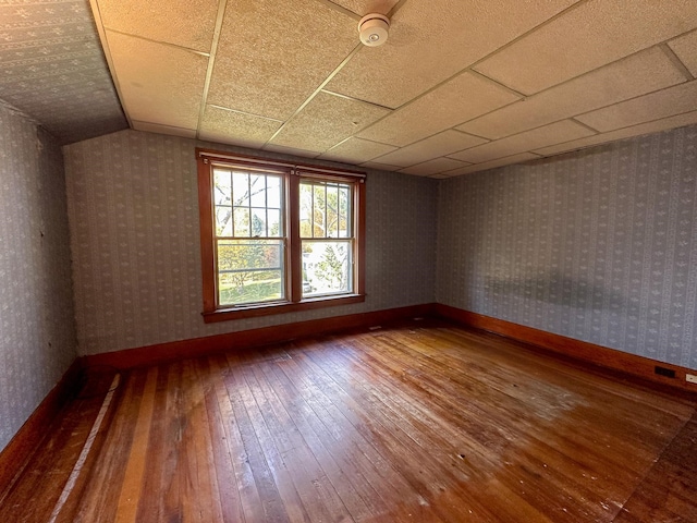 spare room with a paneled ceiling, wood-type flooring, and vaulted ceiling