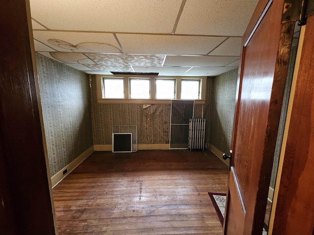 empty room featuring a paneled ceiling and dark hardwood / wood-style flooring